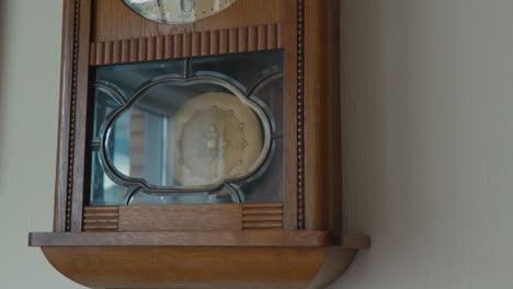 old antique grandfathers clock hanging and ticking on an egg-white wall