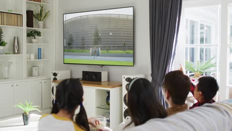 composite of happy family sitting at home together watching athletics javelin event on tv