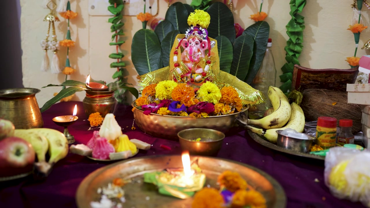 Allestimento tradizionale per la Ganesh Puja con idolo, diya, prasad e decorazioni floreali sacre