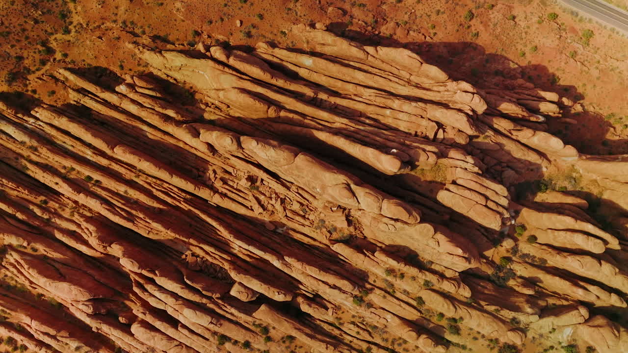 Fascinating rocks of Arches canyon cut like plates by the wind. Highway with a car moving by beside the mountains. Top view.
