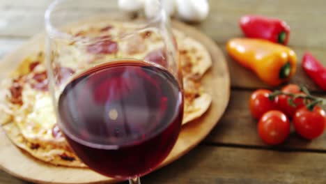 una deliciosa pizza con un vaso de vino, verduras y especias