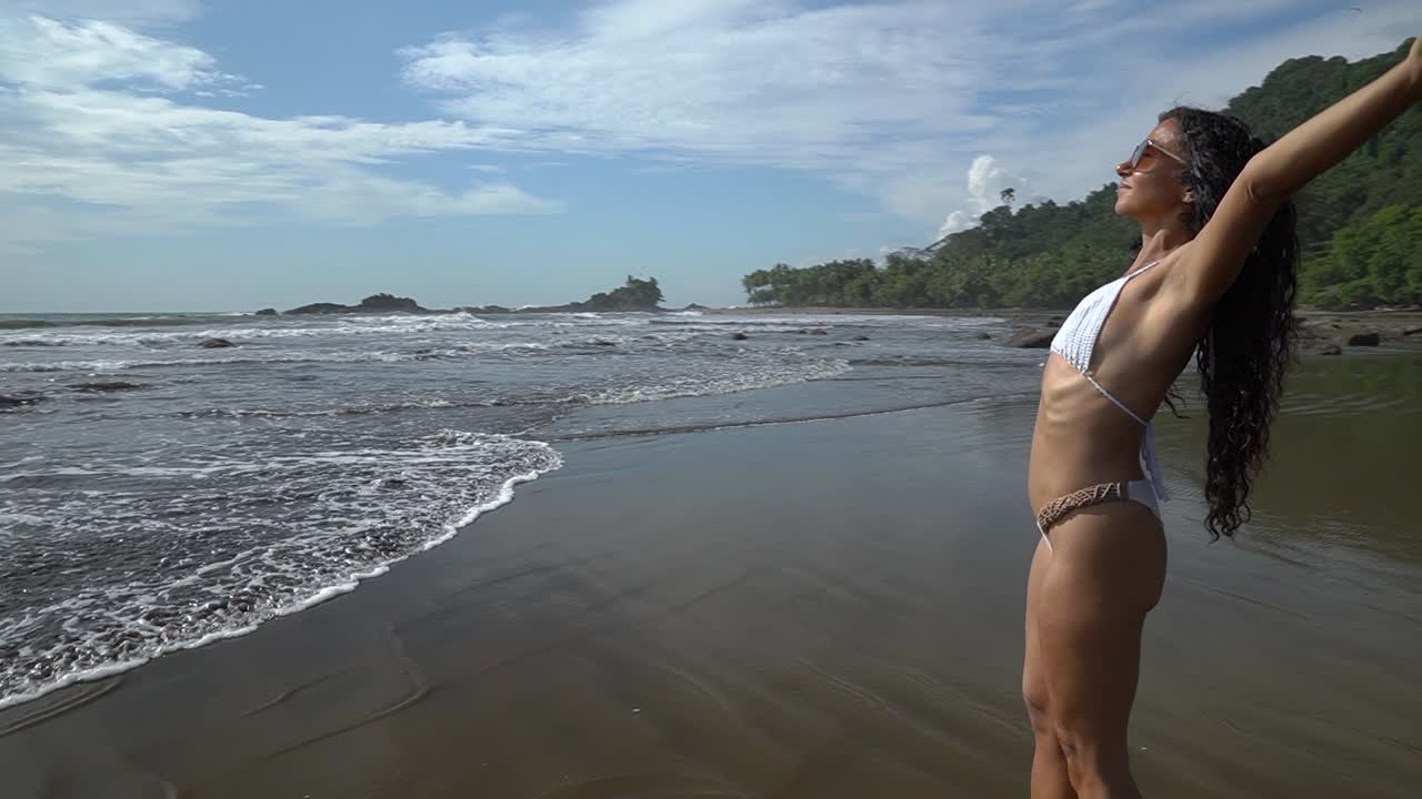 Giovane donna che si gode il caldo sole estivo su una spiaggia sabbiosa.
