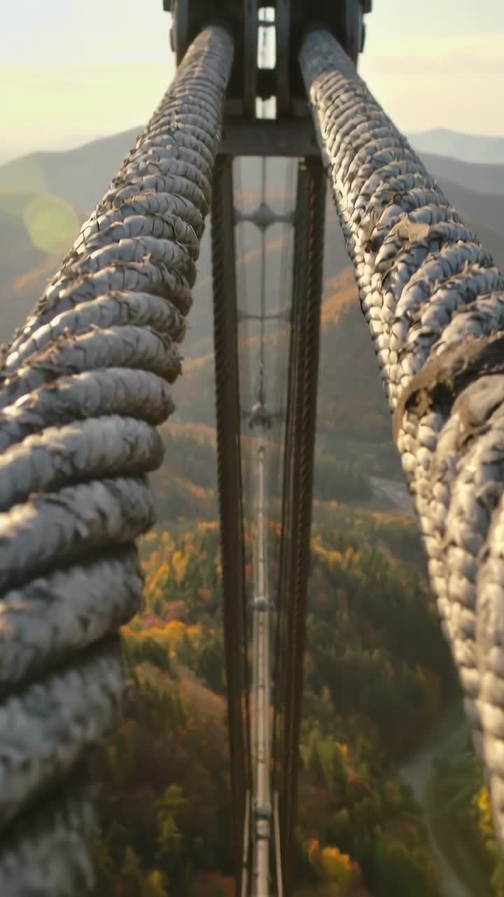 Video verticale: Telecamera in movimento dall'ancoraggio lungo il ponte che mostra cavi intrecciati e la valle per la scala