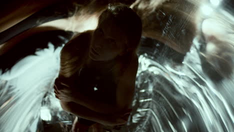woman sitting curled up, gazing at her distorted reflections around