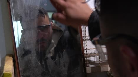 Man-cleaning-a-very-old-mirror-on-his-workshop