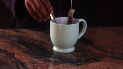 placing tea cup on table and removing the teabag from a colorful cup of tea