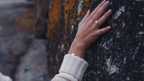 cerca de la mano de la mujer tocando la roca explorando la costa disfrutando de la aventura