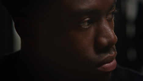 close up of unhappy and depressed young man sitting on sofa at home at night closing eyes and shaking head