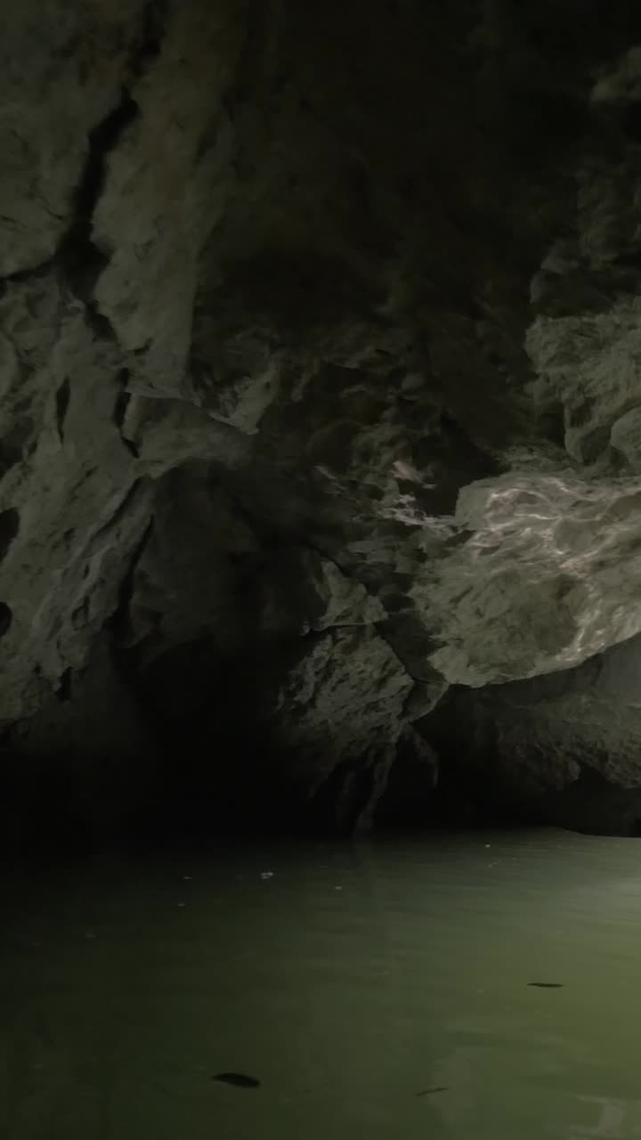Barca che esce da una grotta buia in un paesaggio fluviale luminoso e panoramico