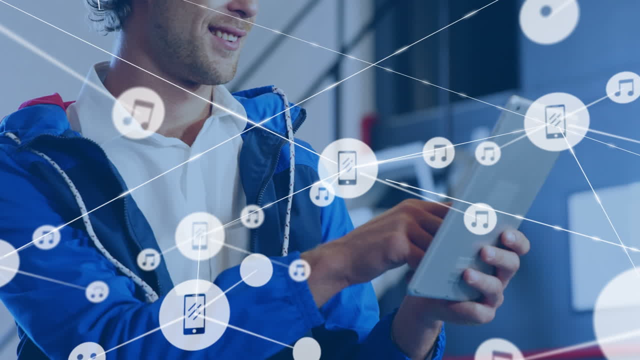 animación de una red de iconos digitales contra un hombre caucásico feliz usando una tableta digital en la oficina