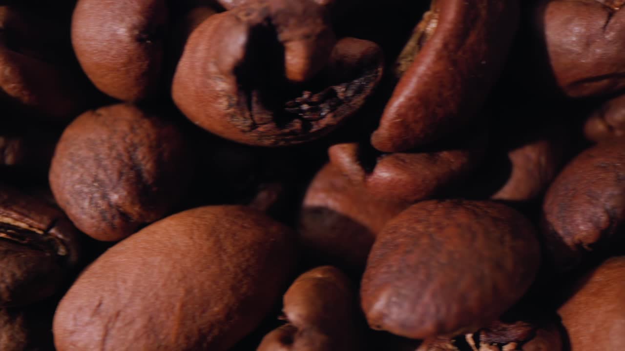 Fast super close up top down slider footage of freshly roasted beans in a pile.