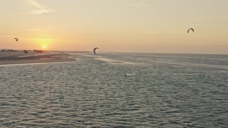 drone tracking guriu kite surfers che giocano nel bagliore del tramonto sull'orizzonte dell'oceano