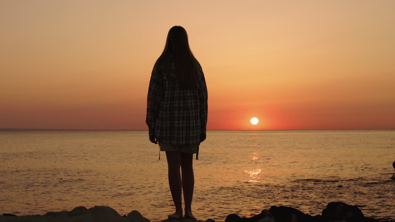 Woman watching the sunset over the sea