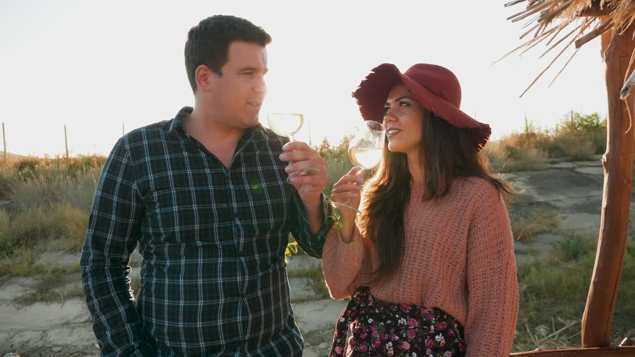 una pareja degustando vino a la cálida luz del atardecer.