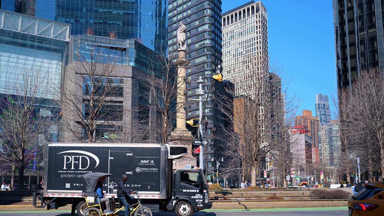 New York, USA, 26 March 2026: Columbus Circle monument surrounded by modern skyscrapers in Manhattan. Stone statue on tall pillar with glass office buildings and blue sky in New York