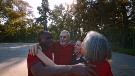 grupo de ancianos en círculo abrazándose celebrando la victoria en un juego de fútbol