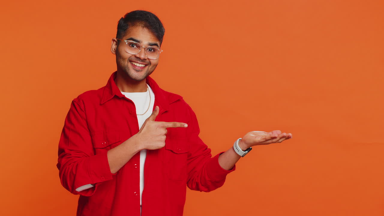 joven mostrando los pulgares hacia arriba y apuntando a la derecha en el espacio en blanco lugar para su logotipo de publicidad