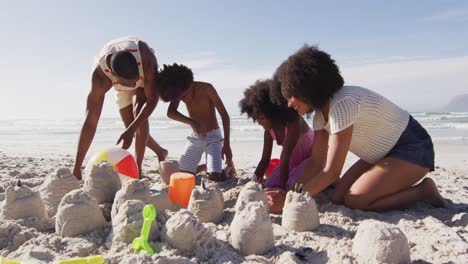 african american parents and their children playing with sand on the beach