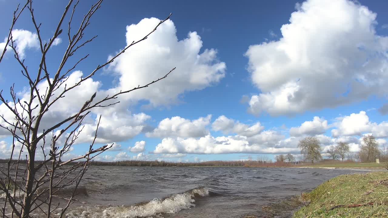 кумулусные облака движутся в голубом небе над озером.