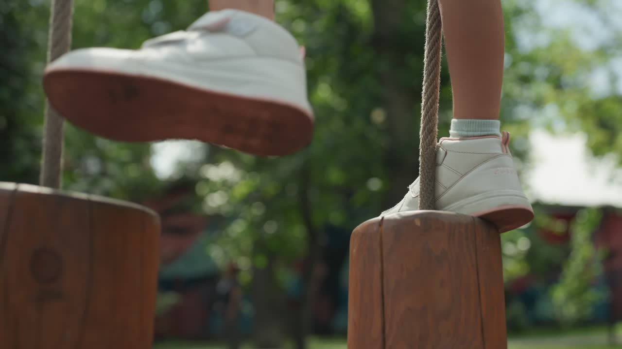La bambina passeggia con sicurezza. Una giovane ragazza cammina con fermezza su travi di legno. Una giovane ragazza mantiene con successo l'equilibrio mentre cammina lungo pali di legno in un ambiente di parco all'aperto e soleggiato.