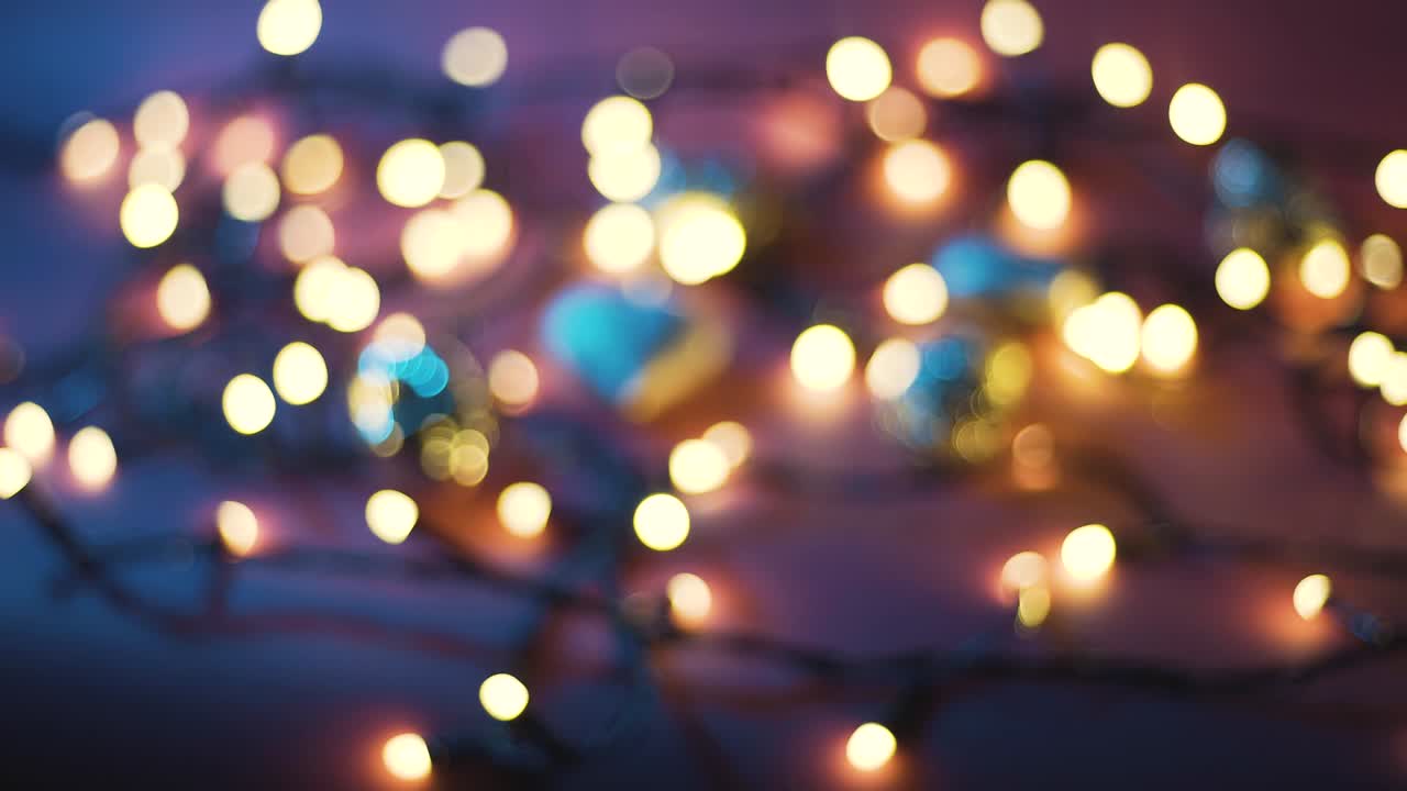 Close-up shot of garland with golden lights and christmas toys on color background. Christmas concept. Home decor. Beautiful bokeh