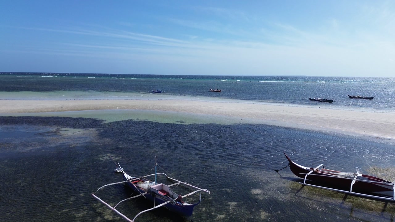 Aerial view of traditional Bangka boats floating on calm tropical sea with clear water creating a peaceful minimal coastal scene around Bantayan Island Philippines Southeast Asia