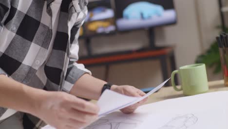 close up of asian male organizing papers while working about car design sketch on table in the studio