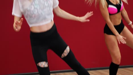 hermosa chica sexy en un fondo rojo con una pared realizar ejercicios de fitness en zapatos con un resorte. entrenamiento cardio en el estilo de salto. salto sin detenerse. quema grasa y figura sternafia con botas en los resortes. baile de fitness para la música kango