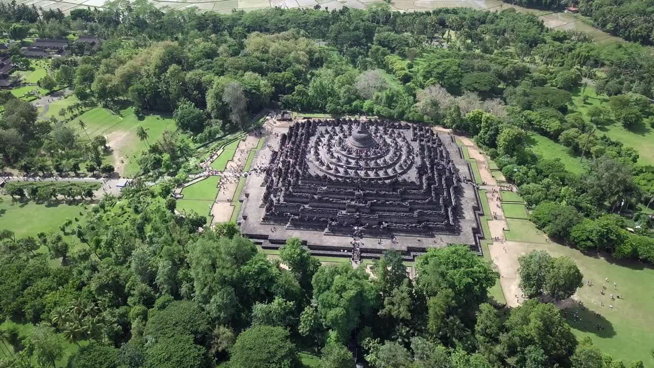 Indonesia,Jawa Island,Yogyakarta, Unesco world heritage Borobudur Temple's drone footage from a distance, covering the whole temple and the surroundings, camera turns around the temple on a sunny day.