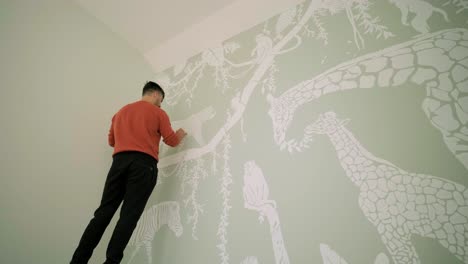 the artist is decorating walls by drawings in the children's room. art painting of the walls in the new house. repair works.