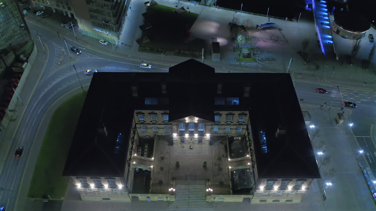 Aerial night view of Belfast Custom House with cars moving around the lit-up historic building