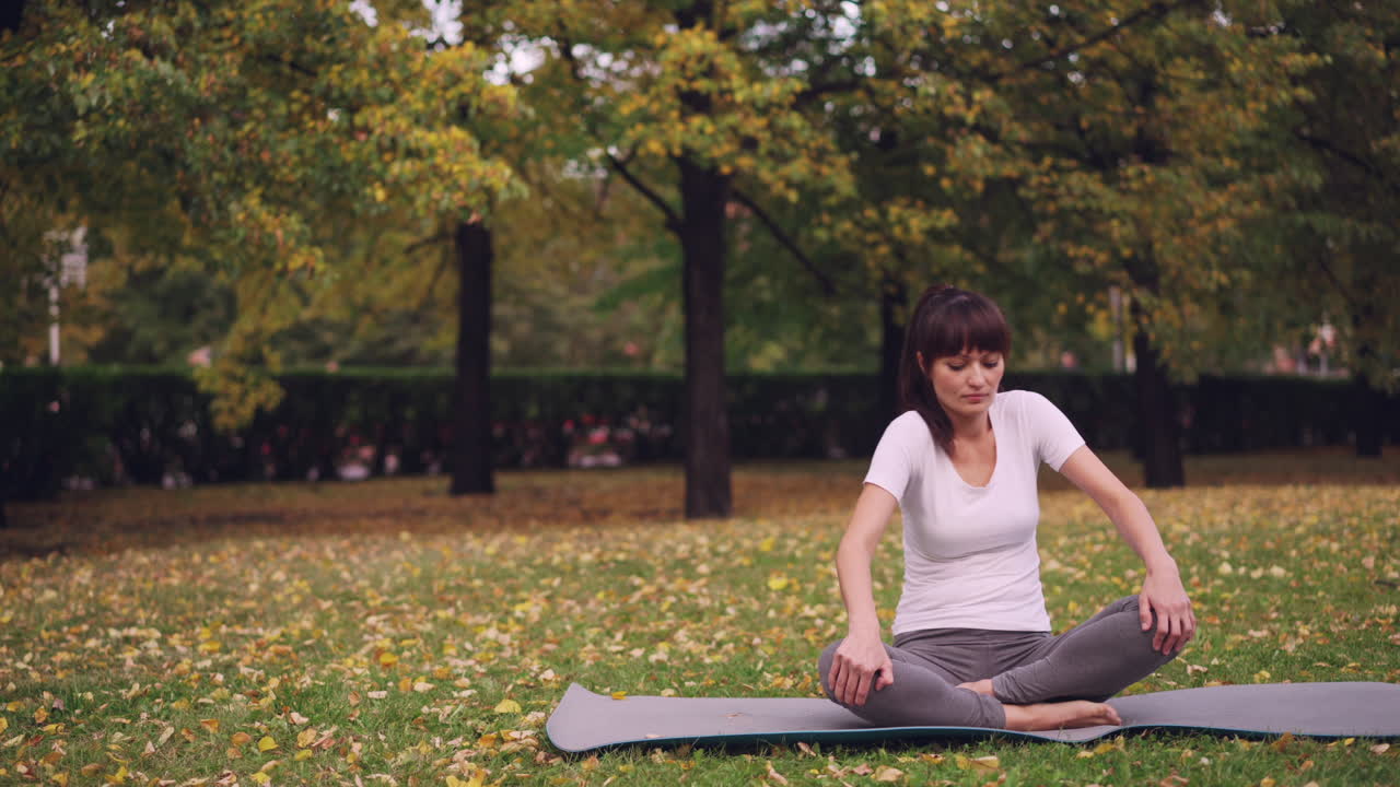 Woman practicing yoga in a park in autumn