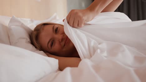 mujer caucásica descansando en la cama en una habitación de hotel