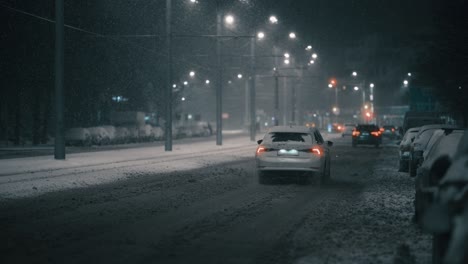 Coche-Conduciendo-Por-La-Ciudad-En-Una-Helada-Noche-De-Invierno,-Durante-Una-Ventisca,-En-Cámara-Súper-Lenta