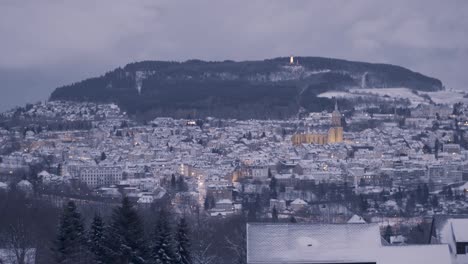 snow-covered town in twilight with distant hills and illuminated buildings