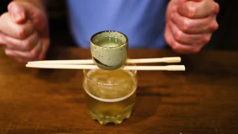 man preparing a beer cocktail with chopsticks