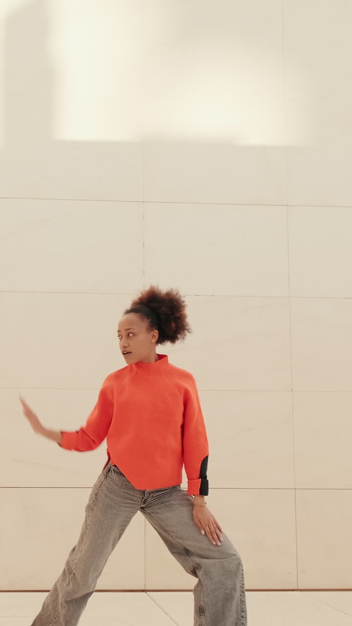 Young Woman Dances Joyfully in Orange Sweater