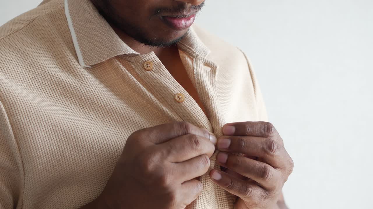 hombre abotonando una camiseta de polo beige