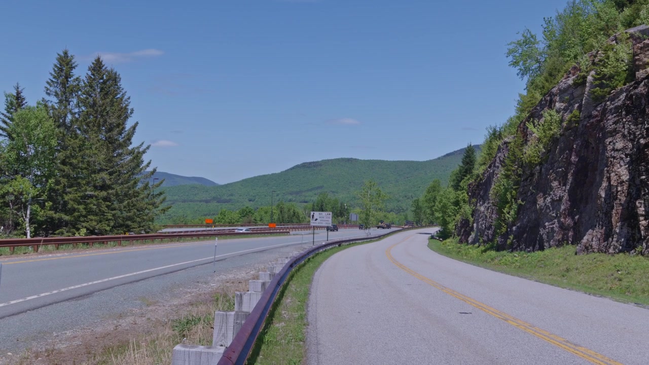Winding mountain highway passing through scenic forested landscape of White Mountain National Forest under blue sky, Franconia, New Hampshire, US