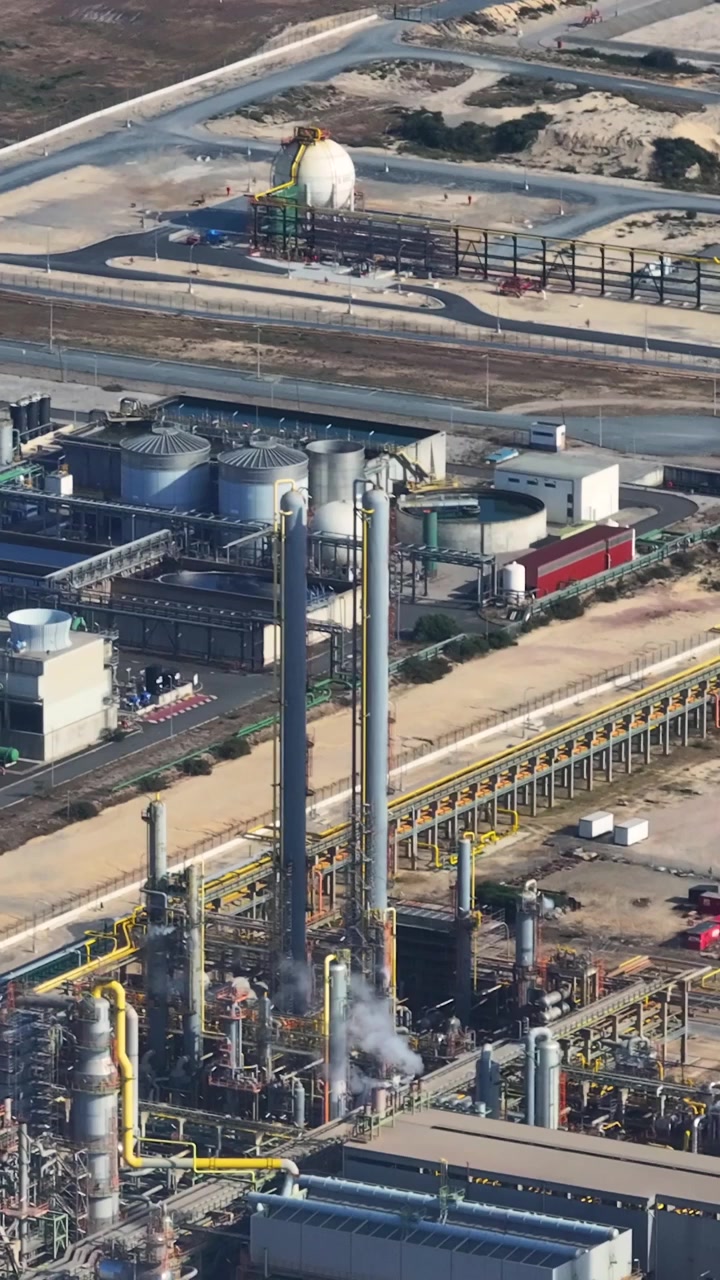 An oil refinery complex is shown in detail with numerous processing units and storage tanks. This industrial area plays a key role in petroleum production and energy supply.