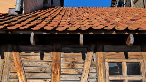 red tiled roof of old wooden house with broken glass window