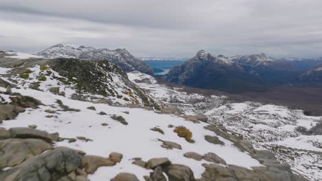 Aerial-Flying-Over-Rock-Cliff-Face-With-Snow-Covered-Landscape-Of-Cardinal-Antonio-Samoré-Pass