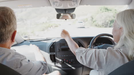 interior view of senior couple on vacation driving hire car along country road