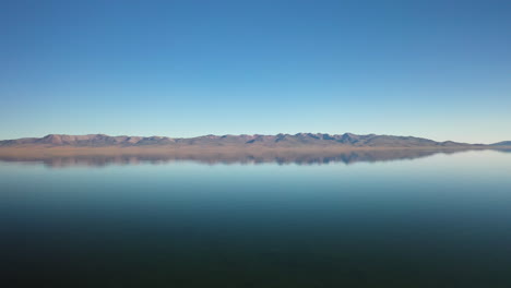epic cinematic revealing drone shot moving over song-kol lake in kyrgyzstan, with the mountains in the distance
