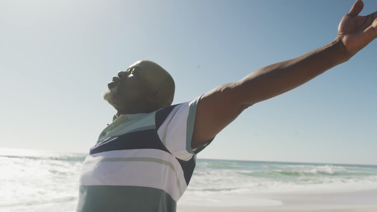 Senior african american man with arms wide on sunny beach