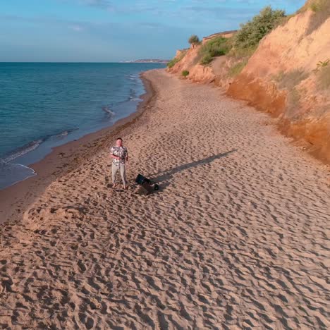 man singing into microphone on beach. aerial view of man singing to microphone on beach