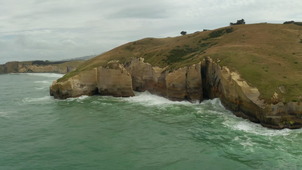 Aerial orbiting right to left shot of cliffs along the coastline in New Zealand during the day
