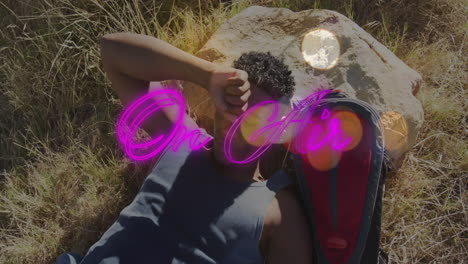 man lying on grass shielding eyes, with neon on air overlay, lens flare in technology tutorial