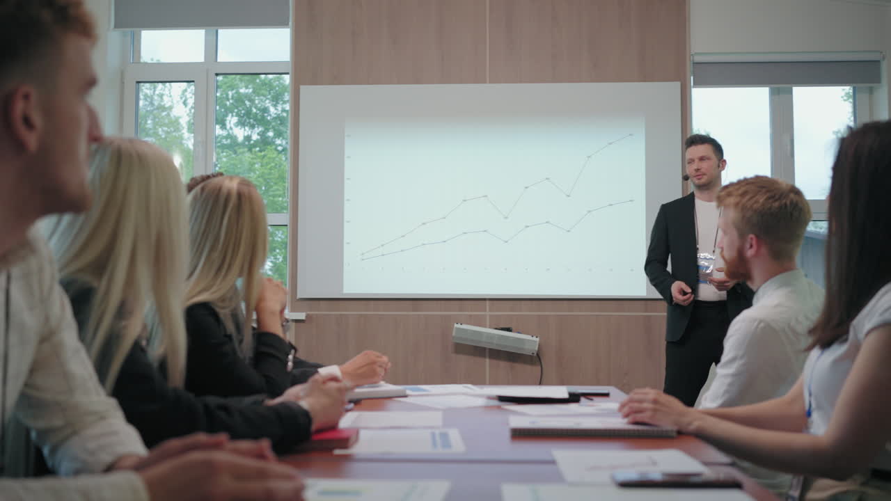 경영자 또는 회사의 수장이 새로운 전략을 설명하는 전문가와 관리자의 앞에서 이야기하고 있습니다.