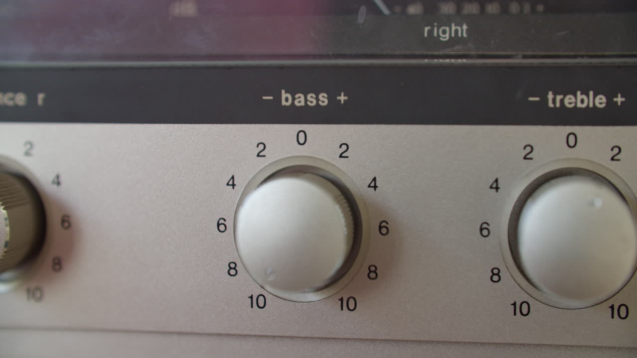 un primerísimo plano de ajuste del mando de graves con la mano izquierda